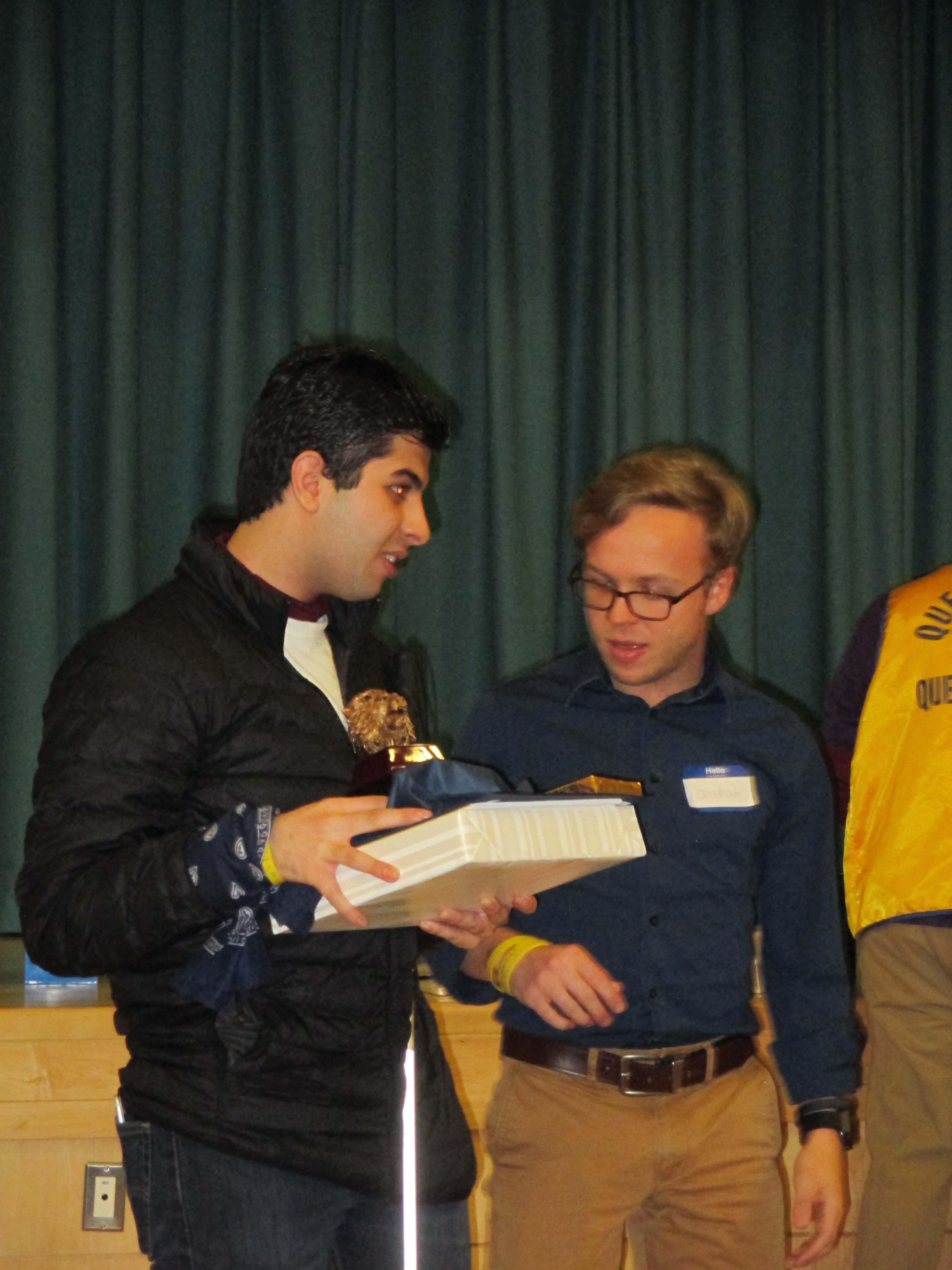 Photo of student with box and trophy in hands standing next to a teacher.